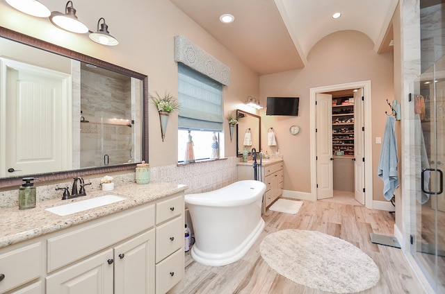 33215 Worthing Ln, Fulshear, TX 77441 - bathroom with a stall shower, two vanities, wood finished floors, a soaking tub, and lofted ceiling