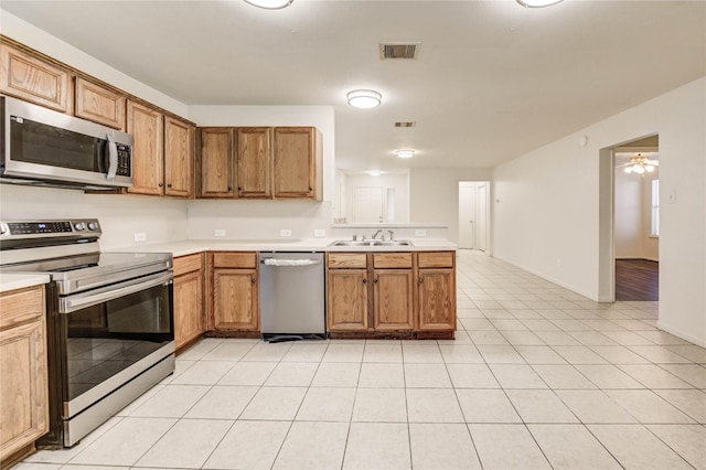 19138 S Whimsey Dr, Cypress, TX 77433 - kitchen featuring appliances with stainless steel finishes, a peninsula, light countertops, brown cabinetry, and light tile patterned floors