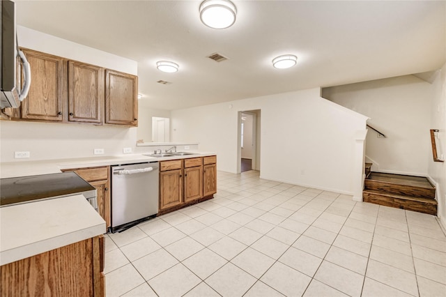 19138 S Whimsey Dr, Cypress, TX 77433 - kitchen with appliances with stainless steel finishes, light countertops, brown cabinets, a peninsula, and light tile patterned floors