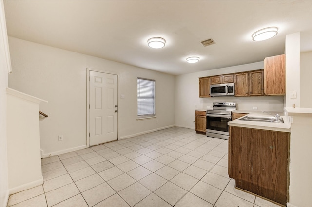 19138 S Whimsey Dr, Cypress, TX 77433 - kitchen featuring appliances with stainless steel finishes, light countertops, light tile patterned floors, and brown cabinetry