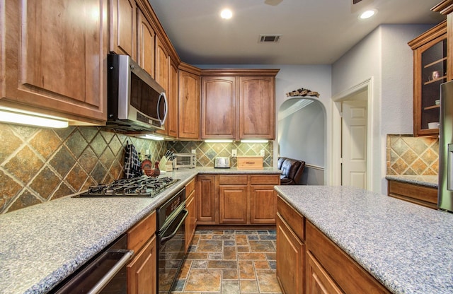 16506 Dawson Mill Ct, Houston, TX 77095 - kitchen with appliances with stainless steel finishes, dark stone finish flooring, tasteful backsplash, glass insert cabinets, and recessed lighting