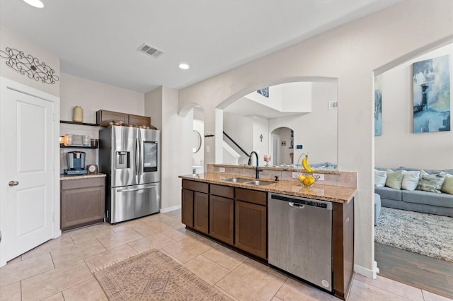 6923 Glenmoor Dr, Rosharon, TX 77583 - kitchen with stainless steel appliances, arched walkways, open floor plan, light stone counters, and dark brown cabinets