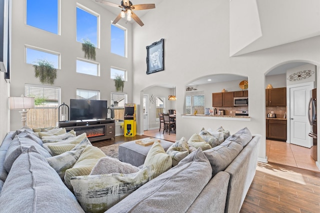 6923 Glenmoor Dr, Rosharon, TX 77583 - living area featuring arched walkways, ceiling fan, a towering ceiling, and light wood-type flooring