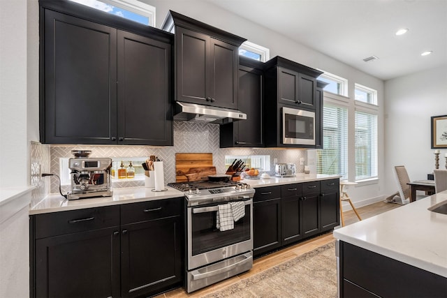 1703 Rosings Way, Katy, TX 77493 - kitchen featuring appliances with stainless steel finishes, under cabinet range hood, dark cabinetry, and recessed lighting