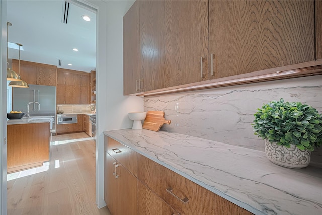 5200 Beech St, Bellaire, TX 77401 - kitchen with light wood finished floors, backsplash, modern cabinets, recessed lighting, and brown cabinetry