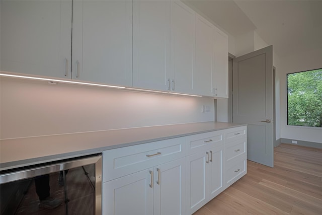 5200 Beech St, Bellaire, TX 77401 - kitchen with wine cooler, light countertops, light wood finished floors, and white cabinetry