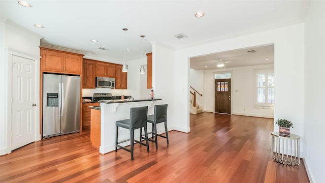 1045 W 16th St, Houston, TX 77008 - kitchen featuring appliances with stainless steel finishes, dark countertops, brown cabinetry, a kitchen breakfast bar, and crown molding