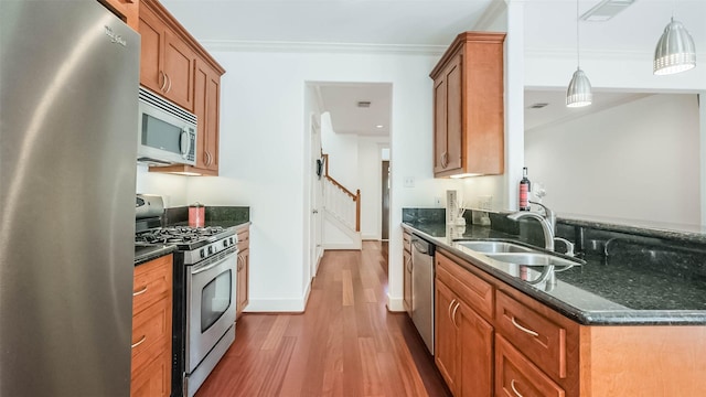 1045 W 16th St, Houston, TX 77008 - kitchen with appliances with stainless steel finishes, crown molding, wood finished floors, brown cabinets, and dark stone countertops
