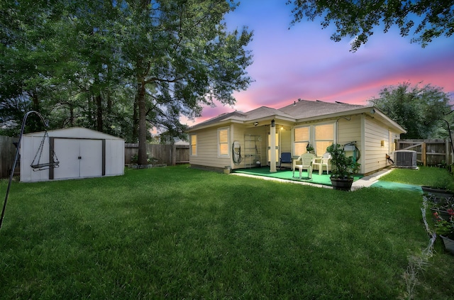 9731 Gulfstream Dr, Conroe, TX 77303 - back of house at dusk featuring a storage shed and a fenced backyard