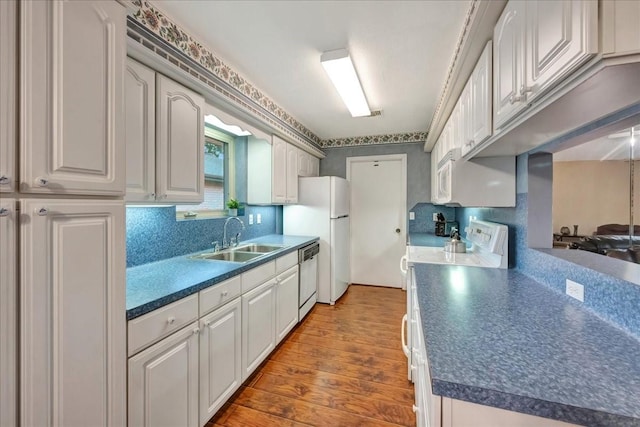 1403 Newport Blvd, League City, TX 77573 - kitchen featuring wood-type flooring, white appliances, dark countertops, backsplash, and white cabinets