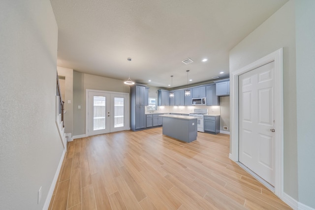 2142 De Soto St, Houston, TX 77091 - kitchen with white gas range oven, stainless steel microwave, a kitchen island, light countertops, and light wood-type flooring