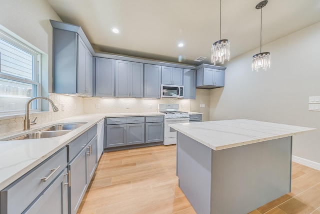 2142 De Soto St, Houston, TX 77091 - kitchen with stainless steel microwave, gas range gas stove, a chandelier, light wood-style flooring, and gray cabinets