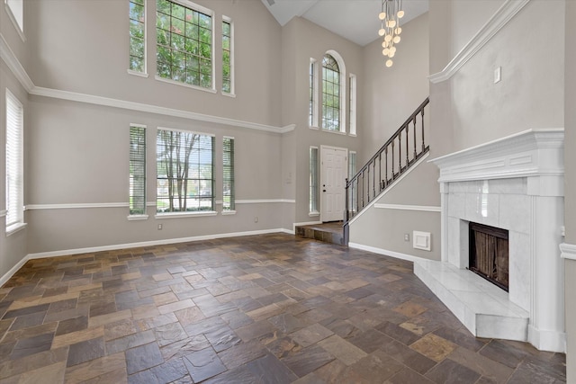 2625 Seashore Dr, Seabrook, TX 77586 - unfurnished living room with a towering ceiling, healthy amount of natural light, stone tile floors, a chandelier, and a fireplace