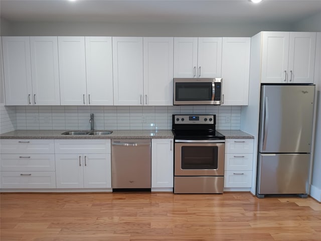 2401 Crawford St Unit A109, Houston, TX 77004 - kitchen featuring appliances with stainless steel finishes, white cabinetry, light wood-type flooring, and tasteful backsplash
