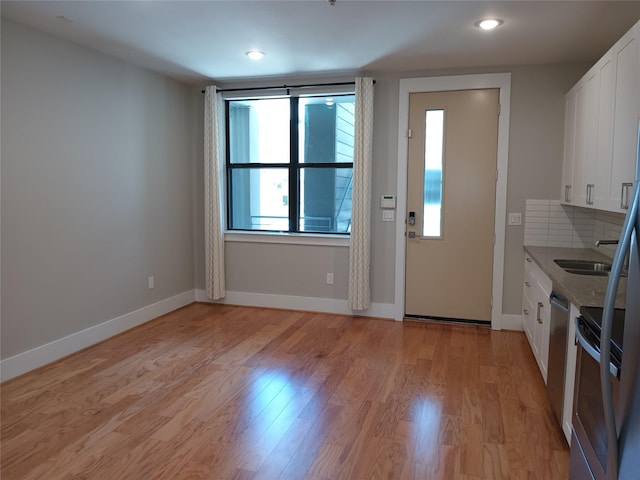 2401 Crawford St Unit A109, Houston, TX 77004 - kitchen featuring stainless steel appliances, white cabinetry, light wood-style flooring, recessed lighting, and backsplash
