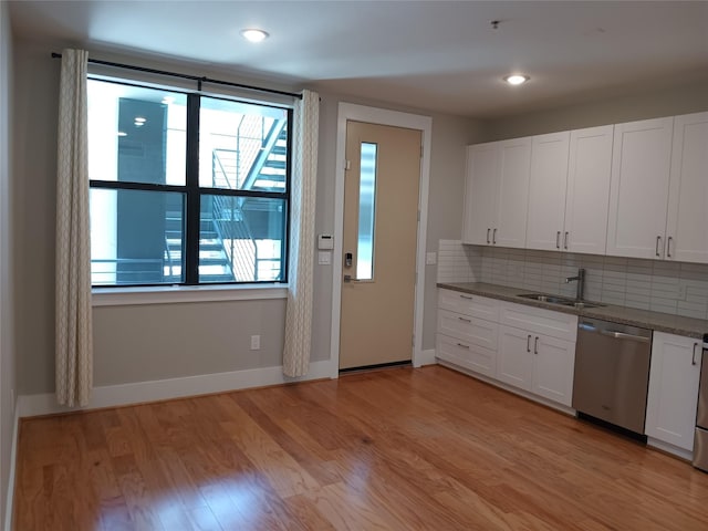2401 Crawford St Unit A109, Houston, TX 77004 - kitchen with stainless steel dishwasher, backsplash, white cabinetry, dark stone countertops, and light wood-type flooring