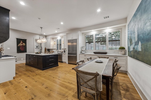 5001 Wedgewood Dr, Bellaire, TX 77401 - kitchen featuring stainless steel appliances, light countertops, a kitchen island, white cabinets, and light wood-type flooring