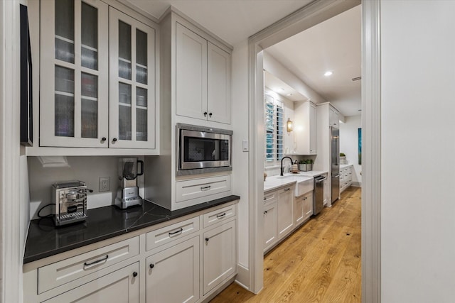 5001 Wedgewood Dr, Bellaire, TX 77401 - kitchen featuring stainless steel appliances, light wood finished floors, glass insert cabinets, recessed lighting, and white cabinetry