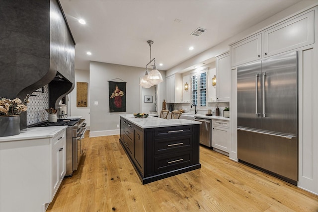 5001 Wedgewood Dr, Bellaire, TX 77401 - kitchen featuring premium appliances, recessed lighting, white cabinetry, a center island, and dark cabinetry