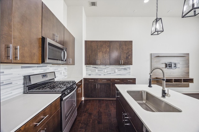 3208 N Macgregor Way Unit C, Houston, TX 77004 - kitchen with appliances with stainless steel finishes, light countertops, dark wood-style flooring, dark brown cabinetry, and decorative backsplash