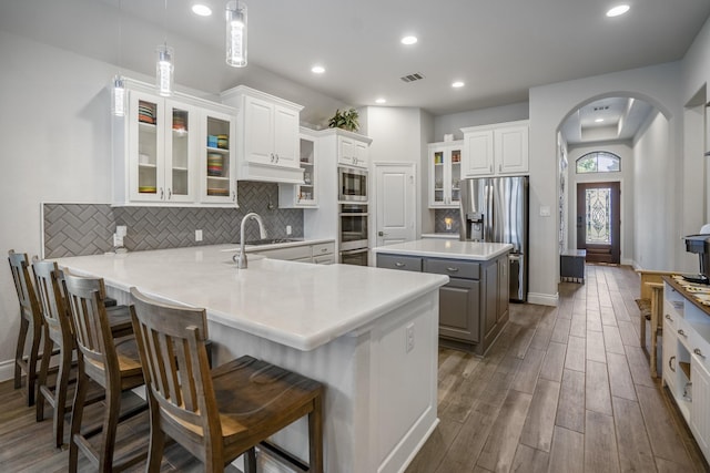 23007 Birchwood Valley Ln, Katy, TX 77493 - kitchen with stainless steel appliances, arched walkways, dark wood-style flooring, decorative backsplash, and recessed lighting