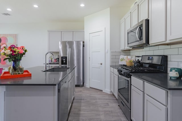 14205 Wonder Lake Ln, Conroe, TX 77384 - kitchen featuring appliances with stainless steel finishes, dark countertops, decorative backsplash, recessed lighting, and light wood finished floors