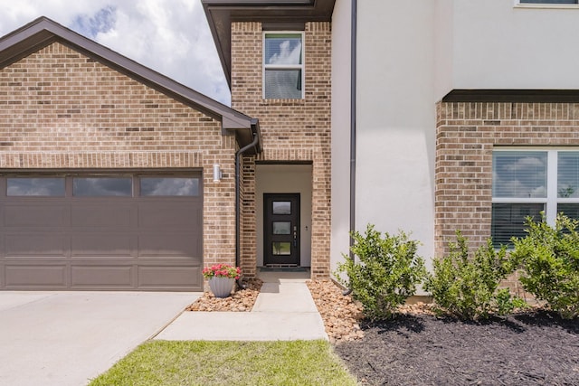 14205 Wonder Lake Ln, Conroe, TX 77384 - view of exterior entry with stucco siding, driveway, brick siding, and a garage