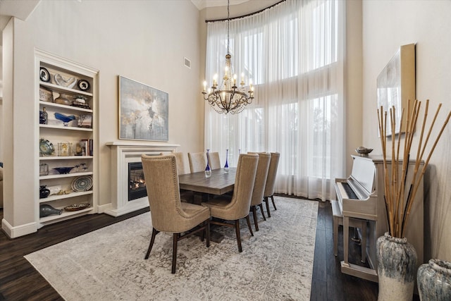 13627 Saddlebred Springs Ln, Cypress, TX 77429 - dining room with a chandelier, a towering ceiling, a glass covered fireplace, wood finished floors, and built in shelves