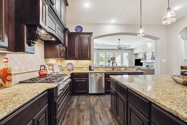 13627 Saddlebred Springs Ln, Cypress, TX 77429 - kitchen with appliances with stainless steel finishes, arched walkways, dark wood-type flooring, a ceiling fan, and light stone countertops