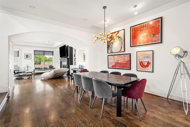 1616 Nevada St, Houston, TX 77006 - dining space featuring arched walkways, a fireplace, dark wood-style flooring, crown molding, and a chandelier