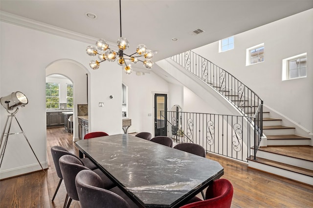 1616 Nevada St, Houston, TX 77006 - dining room featuring arched walkways, a chandelier, dark wood-style flooring, stairs, and crown molding