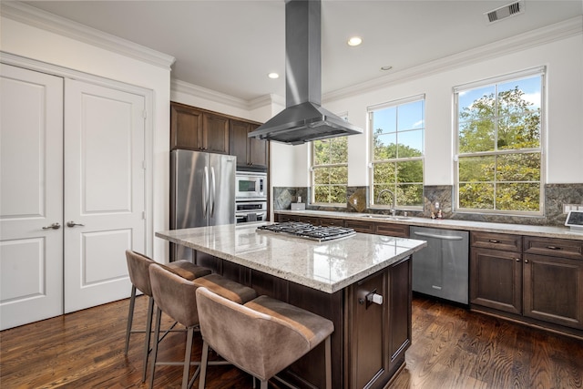 1616 Nevada St, Houston, TX 77006 - kitchen featuring appliances with stainless steel finishes, island range hood, a center island, dark wood-type flooring, and light stone counters
