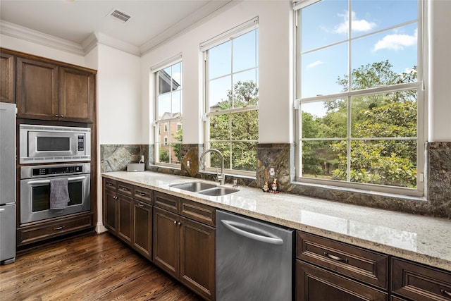 1616 Nevada St, Houston, TX 77006 - kitchen featuring appliances with stainless steel finishes, plenty of natural light, backsplash, dark brown cabinetry, and ornamental molding