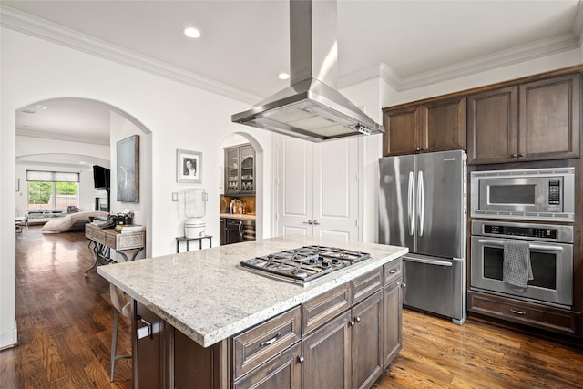 1616 Nevada St, Houston, TX 77006 - kitchen featuring stainless steel appliances, wall chimney range hood, arched walkways, dark brown cabinetry, and light stone countertops
