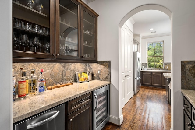 1616 Nevada St, Houston, TX 77006 - indoor dry bar featuring beverage cooler, appliances with stainless steel finishes, arched walkways, dark wood finished floors, and backsplash