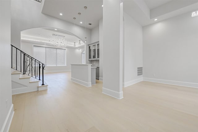2822 Westgrove Ln, Houston, TX 77027 - unfurnished living room featuring light wood-style flooring, recessed lighting, stairs, arched walkways, and a chandelier