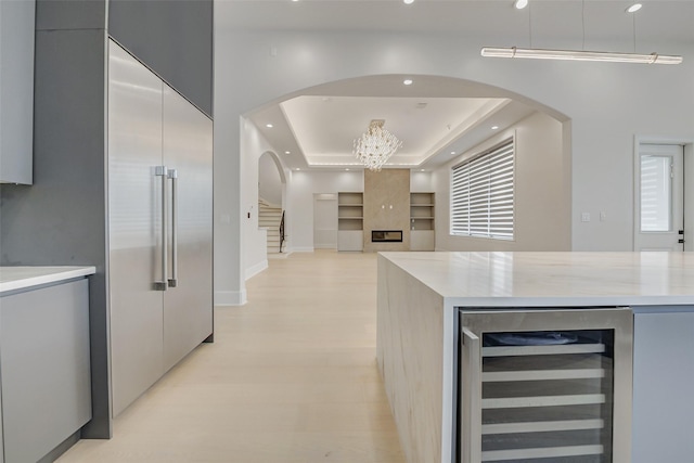2822 Westgrove Ln, Houston, TX 77027 - kitchen featuring beverage cooler, modern cabinets, light countertops, a tray ceiling, and arched walkways