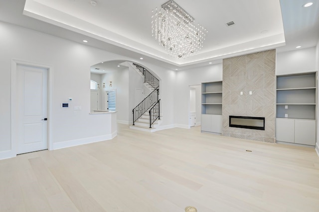 2822 Westgrove Ln, Houston, TX 77027 - unfurnished living room with arched walkways, recessed lighting, a tray ceiling, stairs, and wood finished floors