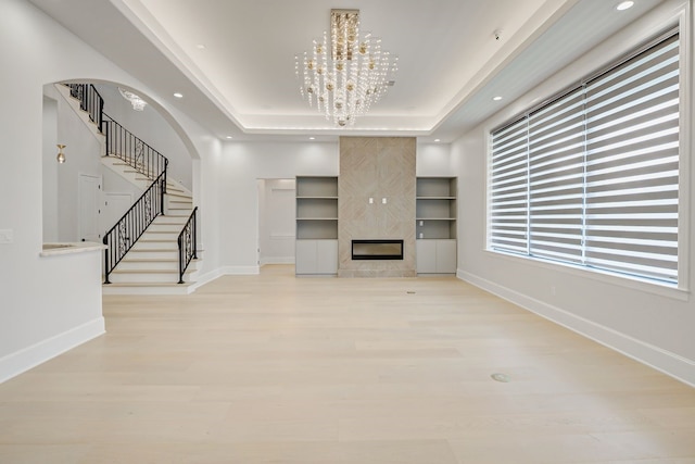 2822 Westgrove Ln, Houston, TX 77027 - unfurnished living room featuring a raised ceiling, light wood finished floors, stairway, arched walkways, and recessed lighting