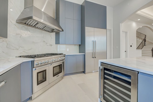 2822 Westgrove Ln, Houston, TX 77027 - kitchen with wall chimney exhaust hood, wine cooler, high quality appliances, gray cabinetry, and tasteful backsplash