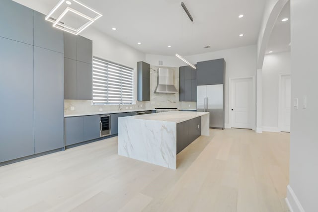 2822 Westgrove Ln, Houston, TX 77027 - kitchen featuring wall chimney range hood, stainless steel built in fridge, modern cabinets, wine cooler, and a center island