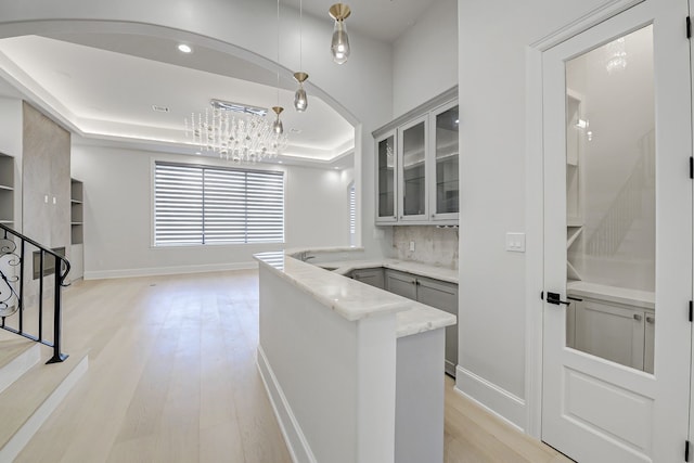 2822 Westgrove Ln, Houston, TX 77027 - bar featuring a raised ceiling, light wood-style flooring, a chandelier, stairway, and backsplash