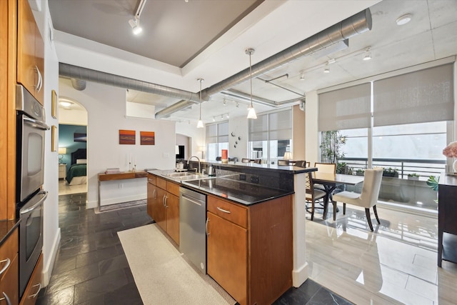 1901 Post Oak Blvd Unit 202, Houston, TX 77056 - kitchen with track lighting, open floor plan, stainless steel appliances, brown cabinets, and a center island with sink