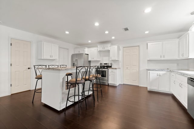 150 Lazy Ln, Livingston, TX 77351 - kitchen with appliances with stainless steel finishes, a breakfast bar, white cabinetry, dark wood finished floors, and recessed lighting