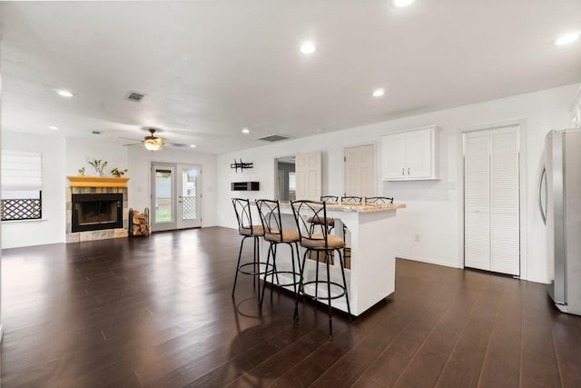 150 Lazy Ln, Livingston, TX 77351 - kitchen with freestanding refrigerator, a breakfast bar, dark wood-style floors, white cabinetry, and recessed lighting