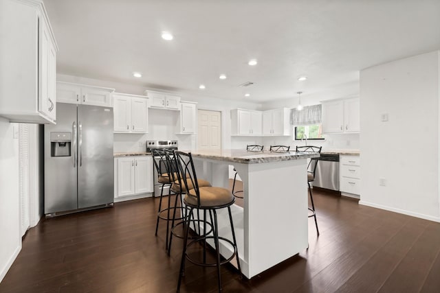 150 Lazy Ln, Livingston, TX 77351 - kitchen featuring stainless steel appliances, a kitchen breakfast bar, a center island, dark wood-style flooring, and white cabinetry