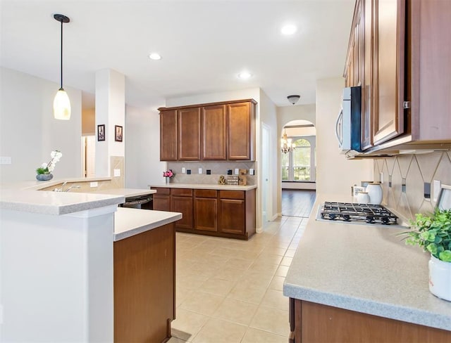 23931 Clover Trl, Katy, TX 77494 - kitchen featuring appliances with stainless steel finishes, arched walkways, tasteful backsplash, light tile patterned floors, and light countertops