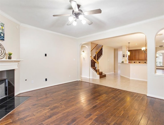 23931 Clover Trl, Katy, TX 77494 - unfurnished living room featuring arched walkways, ornamental molding, wood finished floors, stairway, and ceiling fan