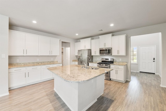 16833 Pink Wintergreen Dr, Conroe, TX 77385 - kitchen with appliances with stainless steel finishes, light wood-style floors, a kitchen island with sink, white cabinetry, and recessed lighting