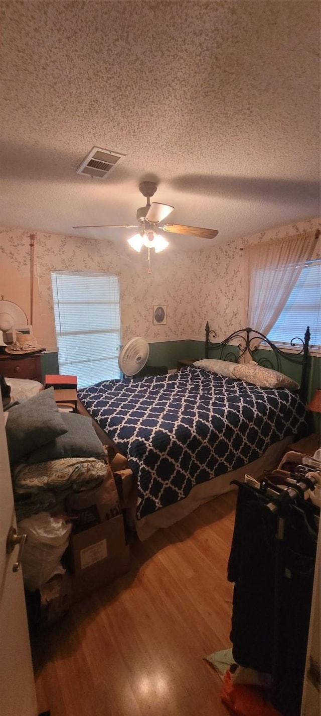 20 Connor Ln, Huntsville, TX 77320 - bedroom with wood finished floors, a textured ceiling, wallpapered walls, and a ceiling fan